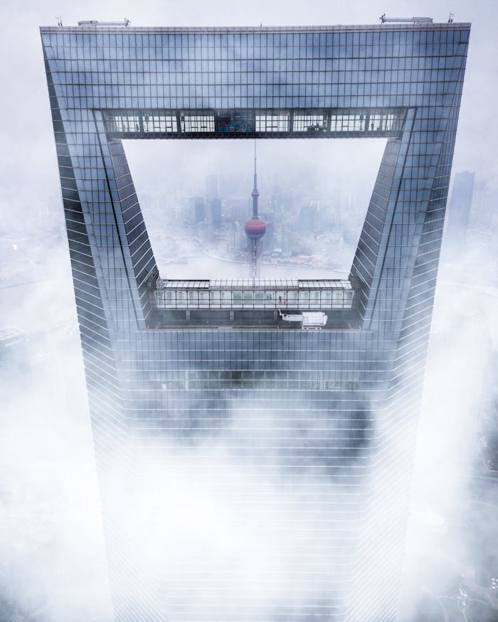 Aerial view of Shanghai World Financial Center in fog, showcasing urban architectural marvels.