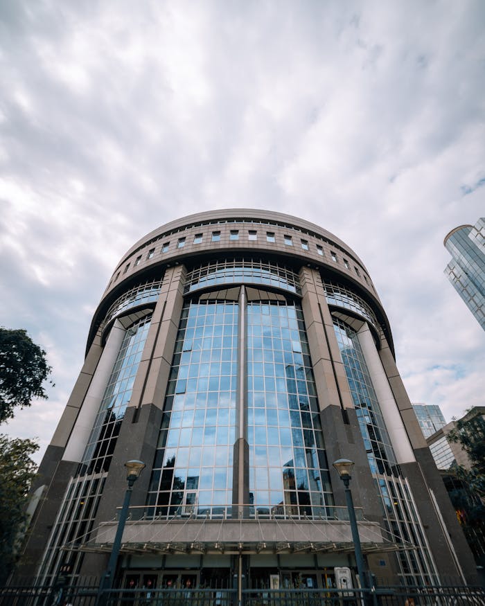 Low angle view of a modern building facade in Brussels, Belgium under a cloudy sky.